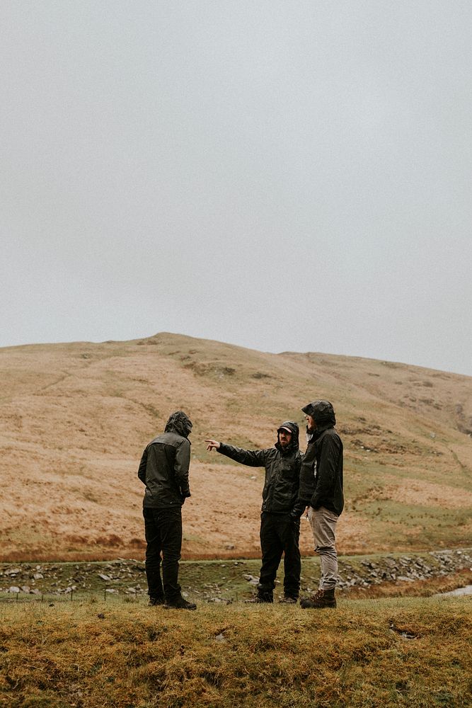 Three men talking outdoors in rainy weather