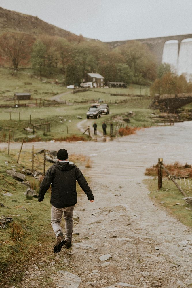 Man walking towards his friends in the countryside with dam structure