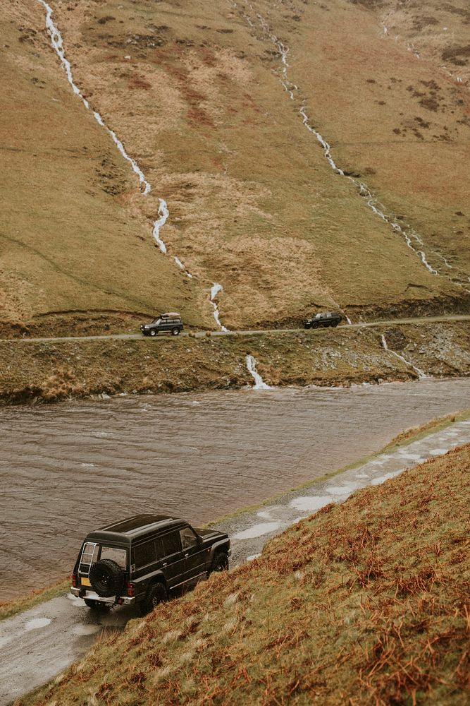 Cars driving by the river on a off-roading path