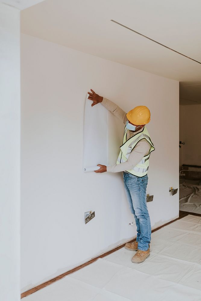 Contractor sticking blank paper on white wall