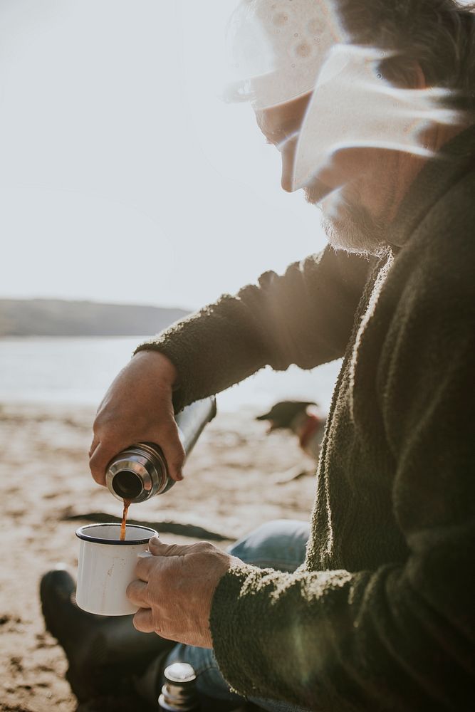 Senior man pouring coffee into a camping mug