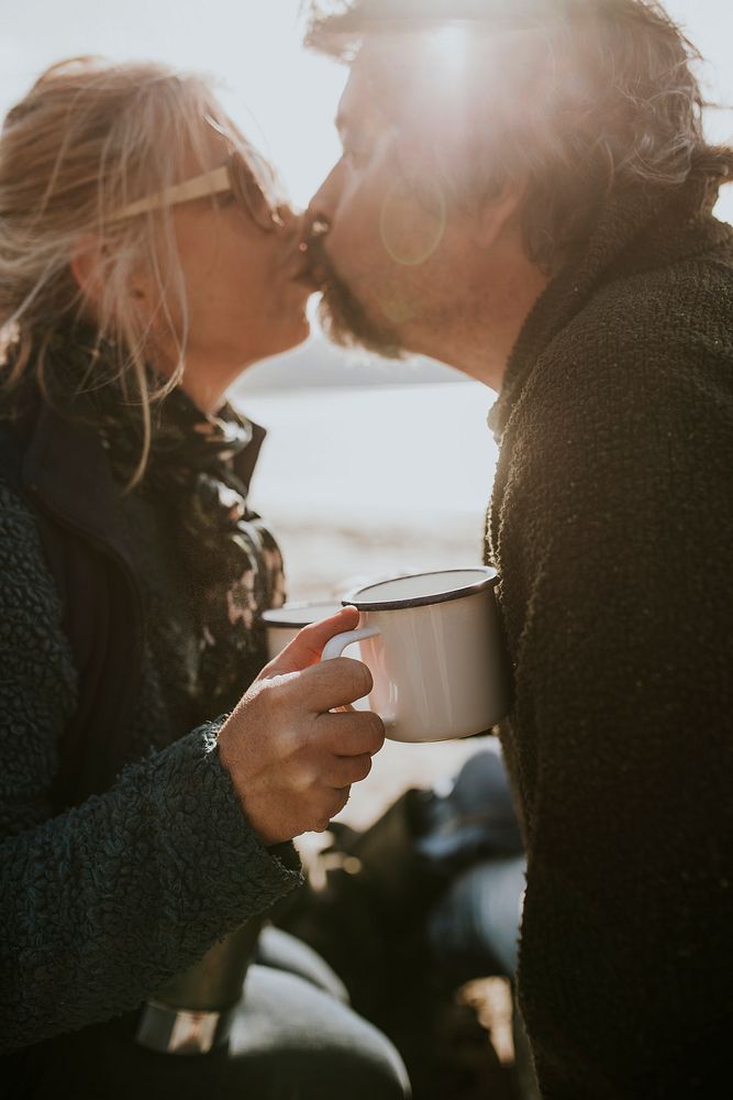 Romantic campers kissing while having morning coffee