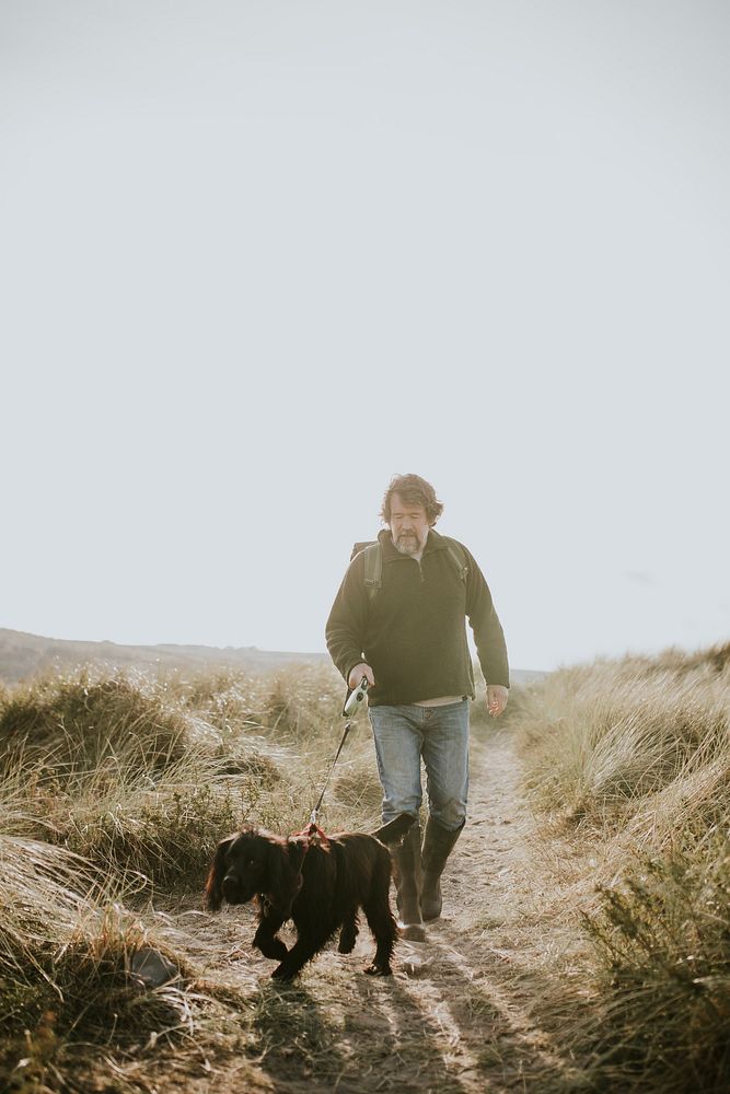 Senior man walking his dog on a coastal trail