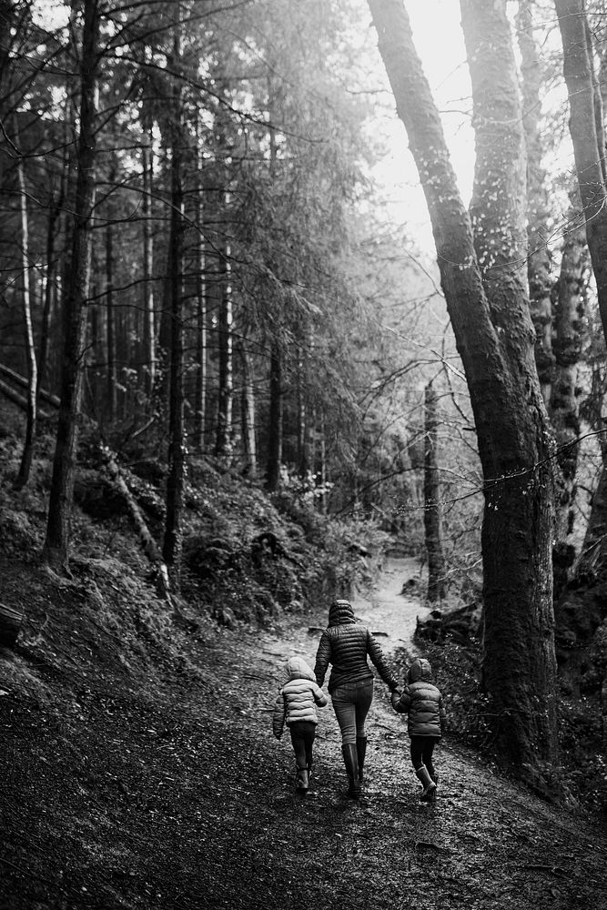 Mother walking with her daughters in the forest rear view black and white