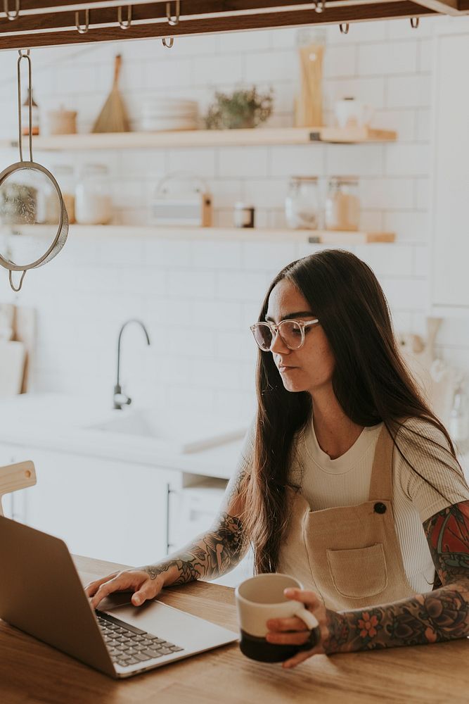 Tattooed woman work from home in her kitchen