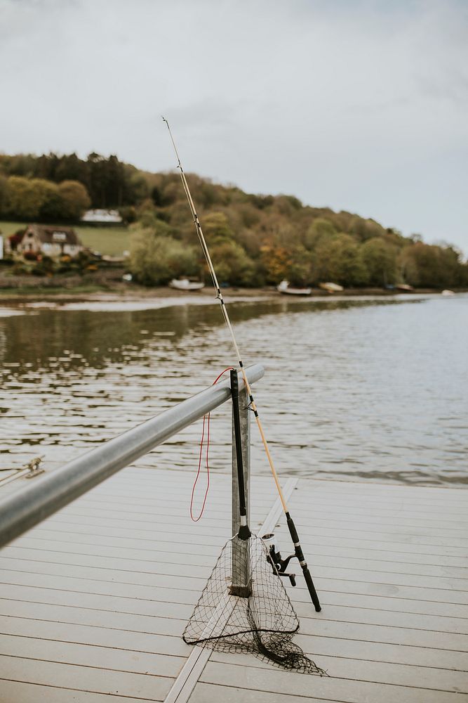 Fishing rod and net on a a lake pier