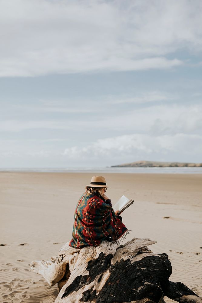Retired senior woman reading a book on the beach