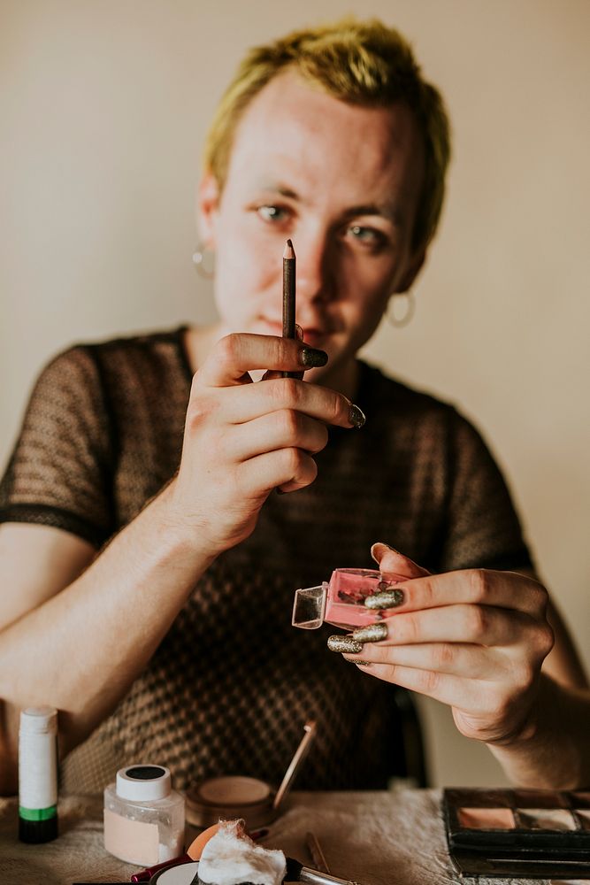 Non-binary person sharpening eyebrow pencil, beauty blogger