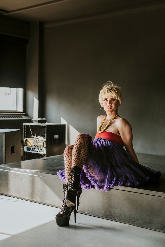 Beautiful drag queen in purple dress sitting on a stage