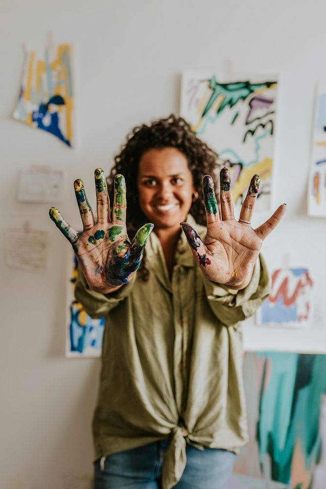 Woman artist showing her hands covered in paint 