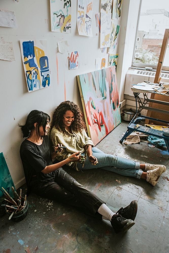 Artist friends sitting on the floor in an art studio 