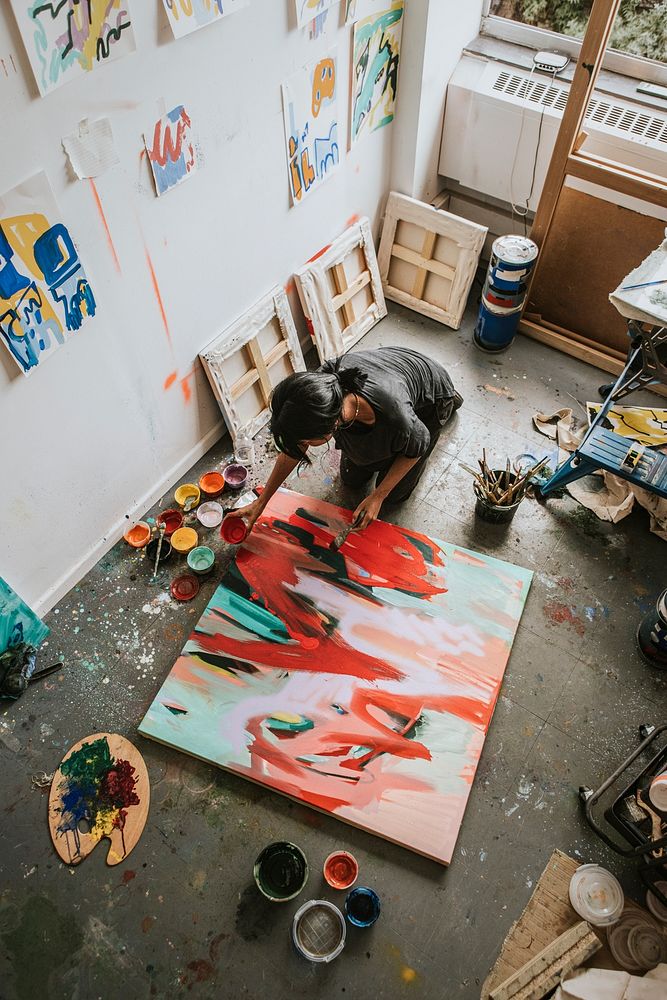 Woman artist working on her paint canvas in her studio 