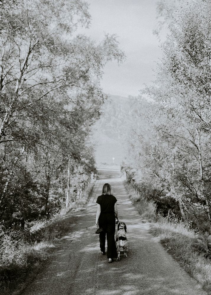 Woman walking dog in countryside