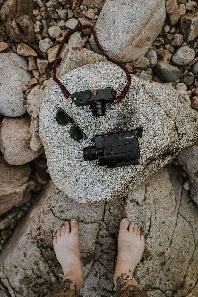 Analog cameras and vintage sunglasses on a rock