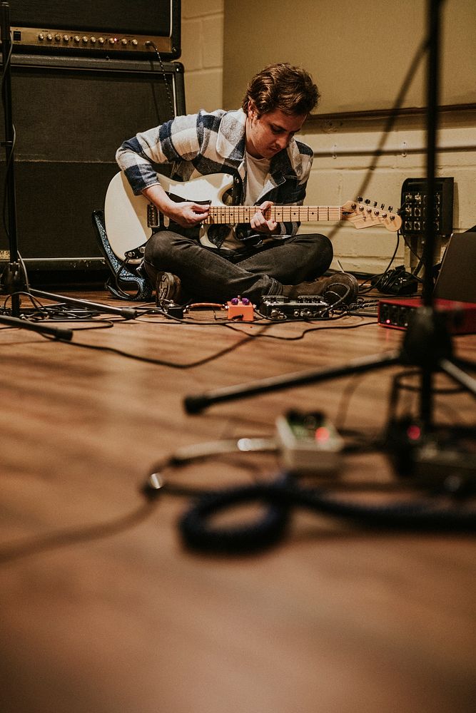 Guitarist playing rock music, studio recoding, sitting on the floor