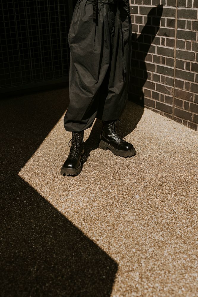 Person wearing black boots standing in the shadow