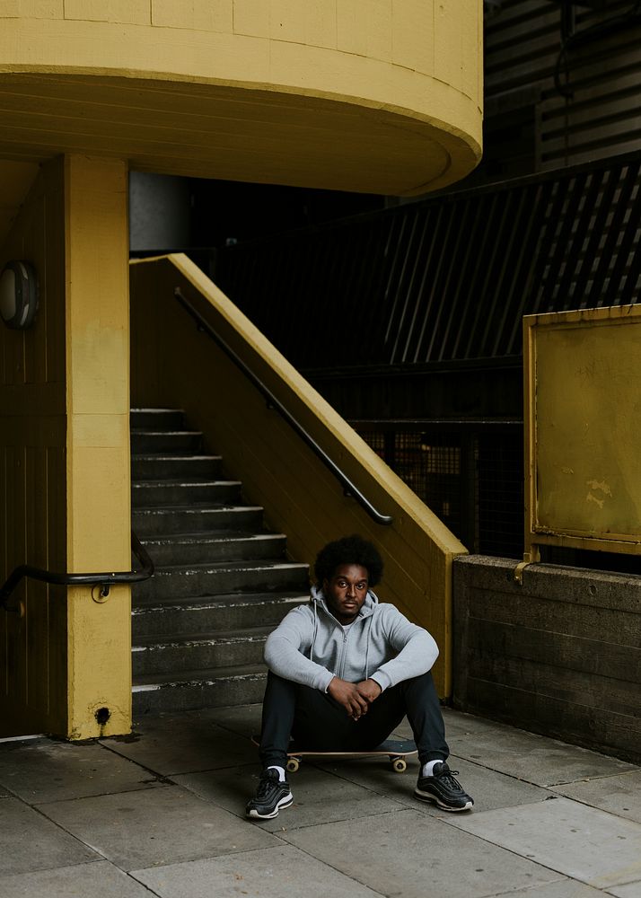 Man sitting on skateboard at yellow stairs