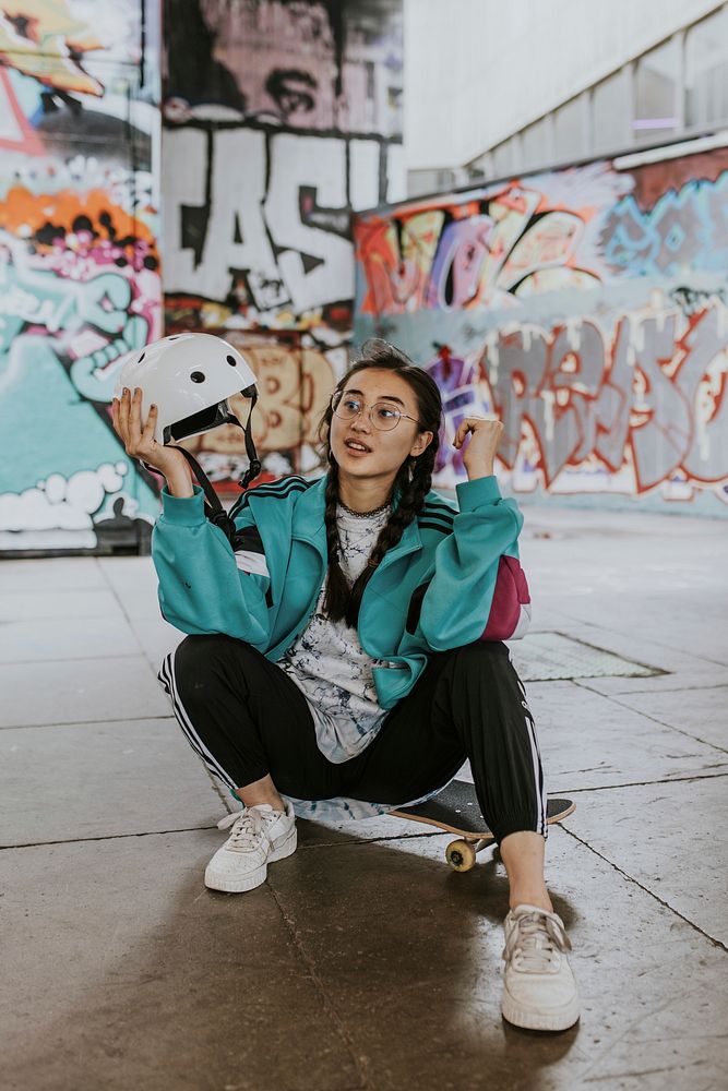 Asian female skater sitting on skateboard