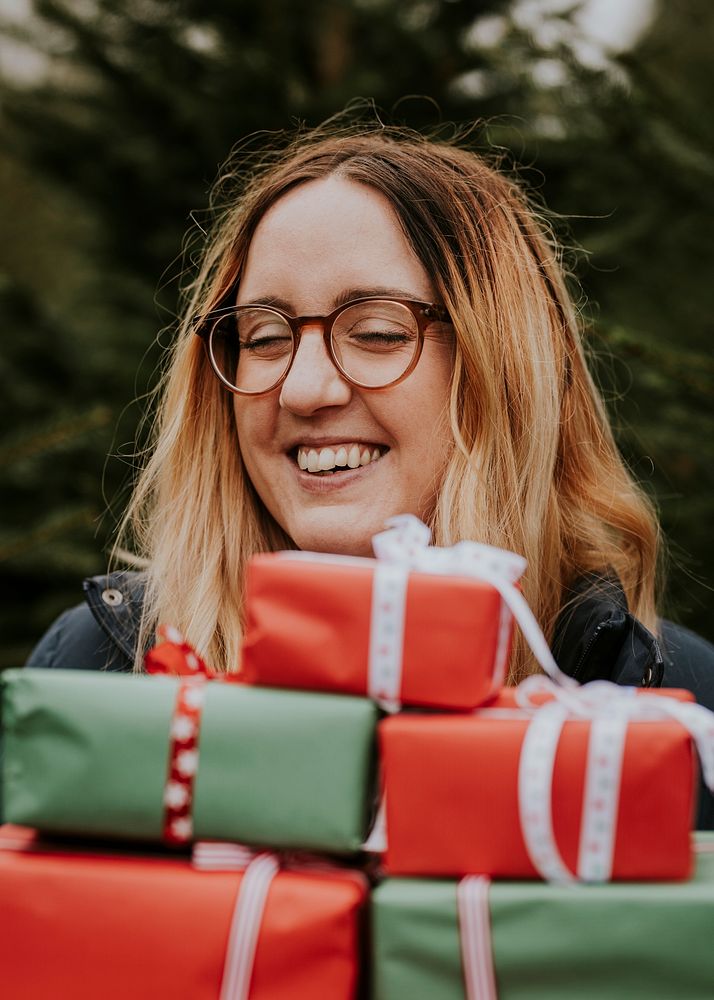 Smiling woman carrying many boxes of Christmas presents
