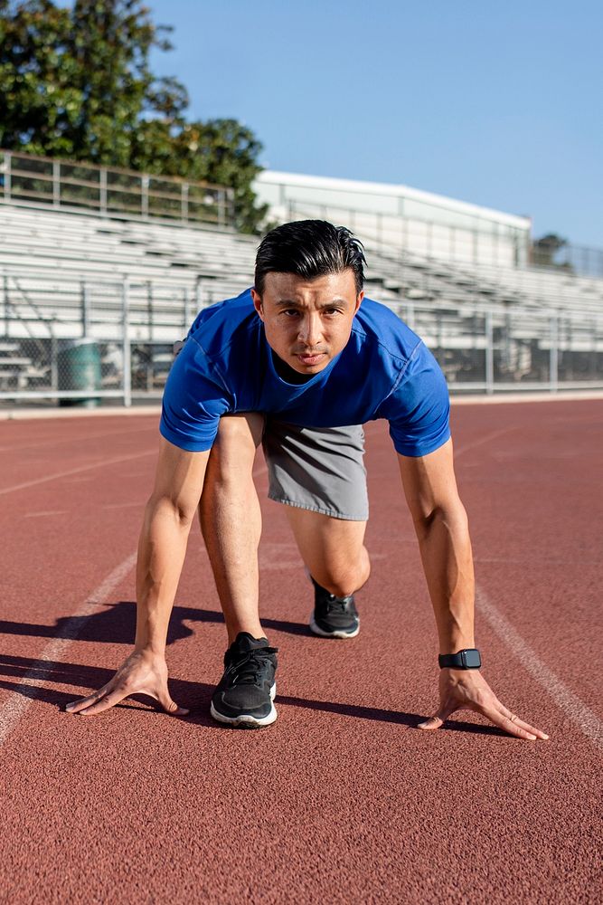 Asian man getting ready to take off on the running track