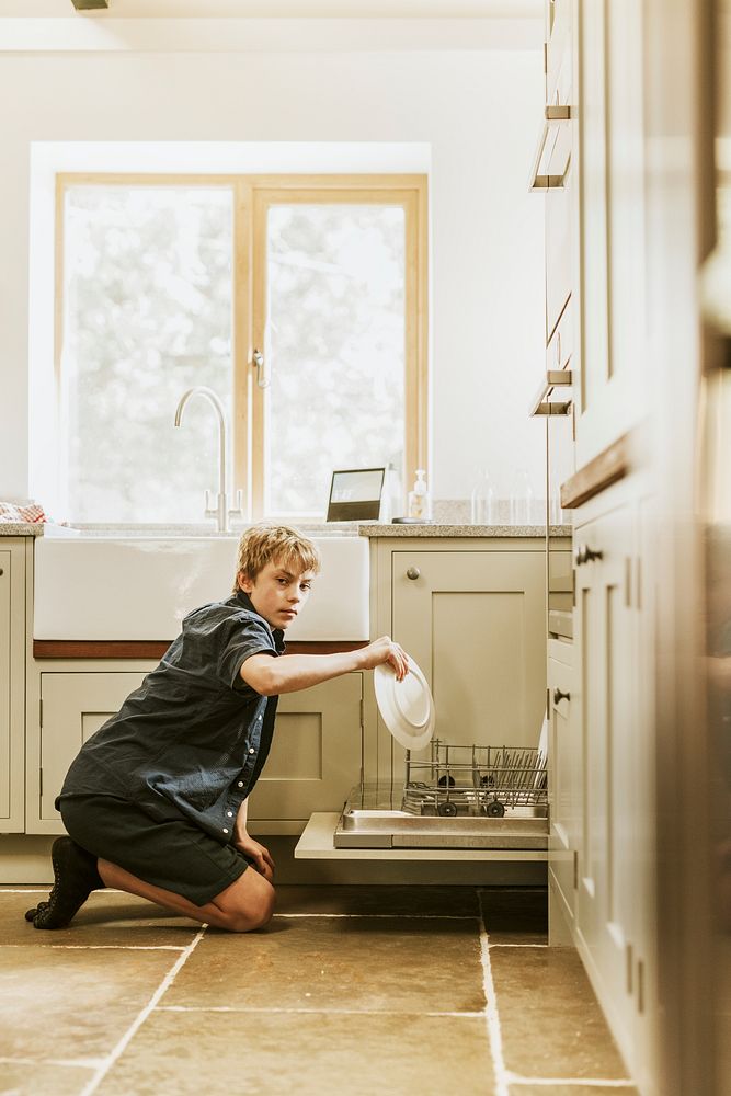 Boy loading dishwasher, basic house chores