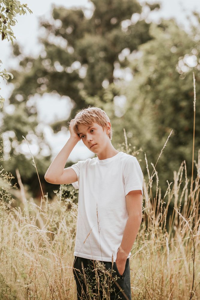 Boy in white tee, summer day in a grass field