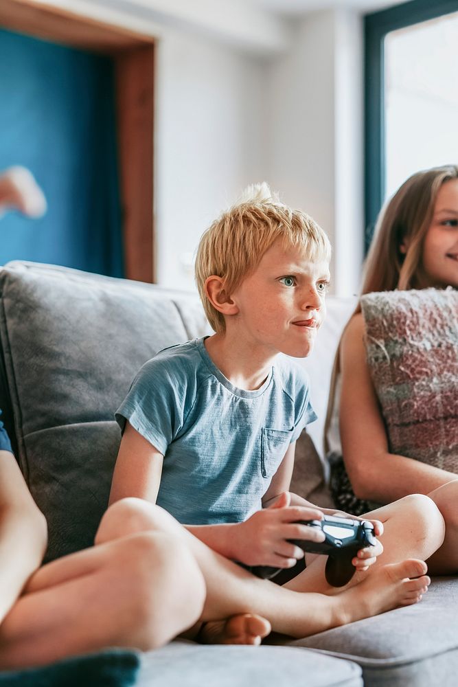 Blond boy playing video game in living room