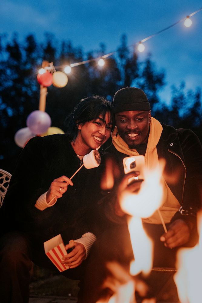 Friends enjoying s'mores and marshmellow together by the bonfire 