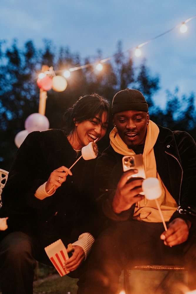 Friends enjoying s'mores and marshmellow together by the bonfire 