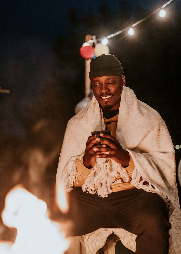 Man keeping warm with hot chocolate, a beanie, and a shawl