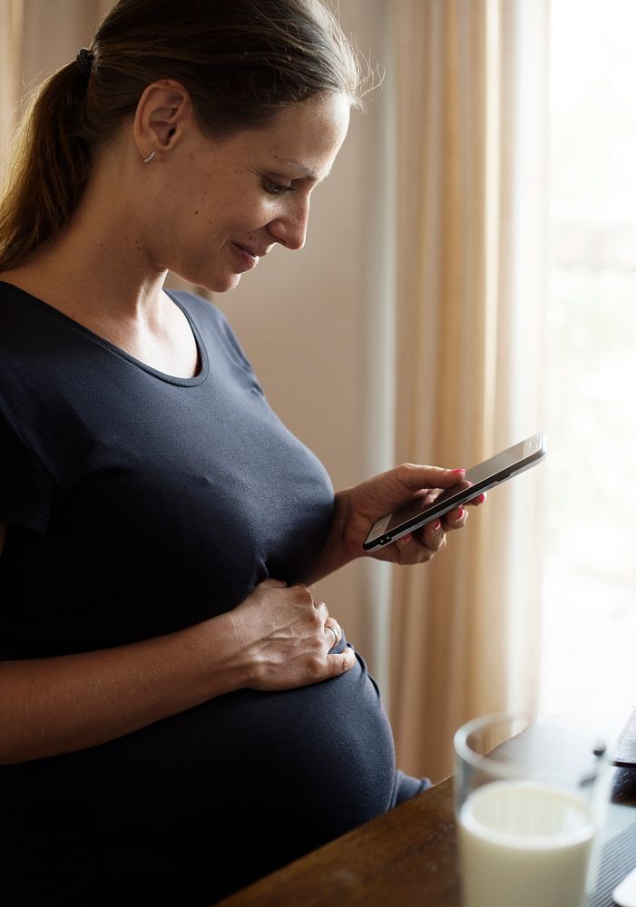 Cheerful pregnant woman using a smartphone