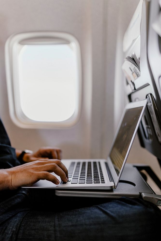 Man using a laptop on a plane. Visit Kaboompics for more free images.