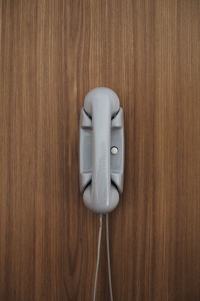 Gray landline telephone on a wooden wall
