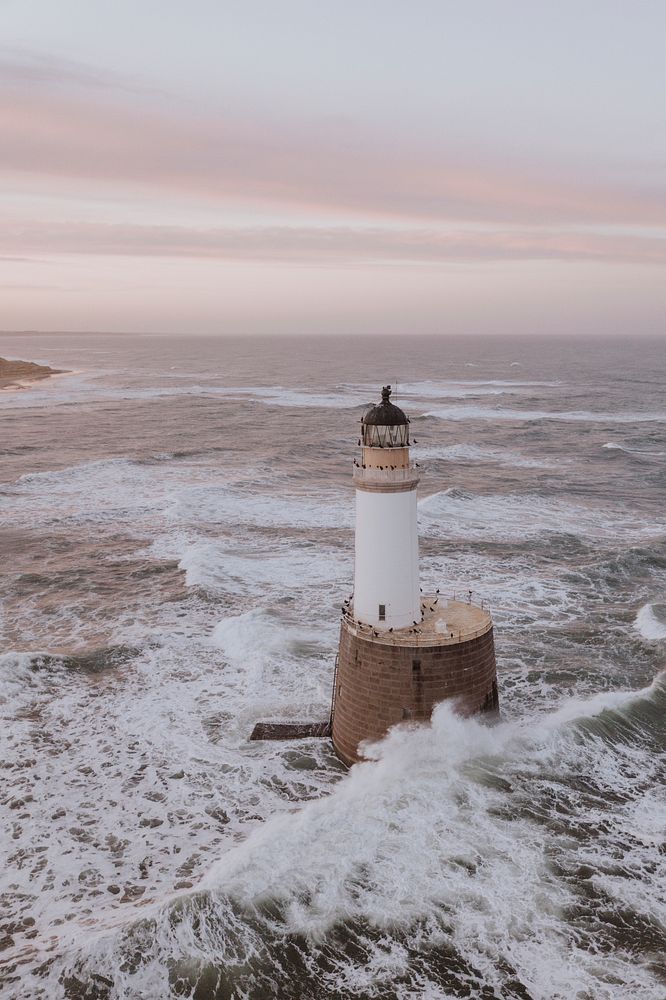 Waves hitting a lighthouse in Scotland