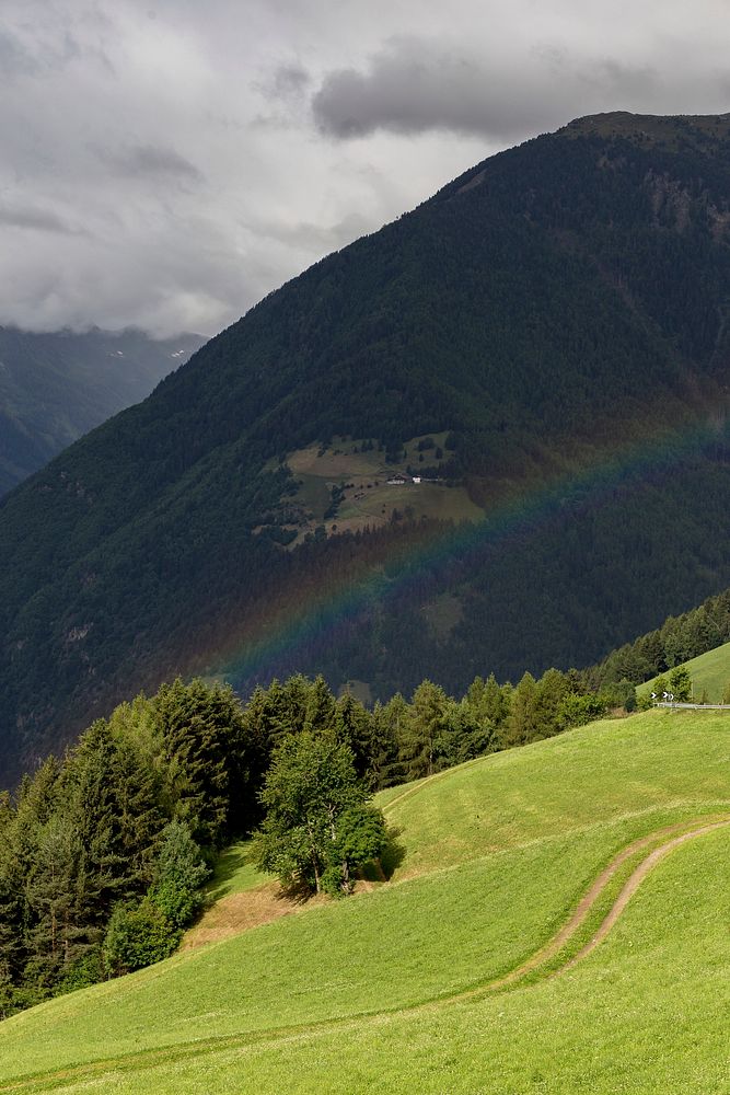 Rainbow going over a mountain and a green hill