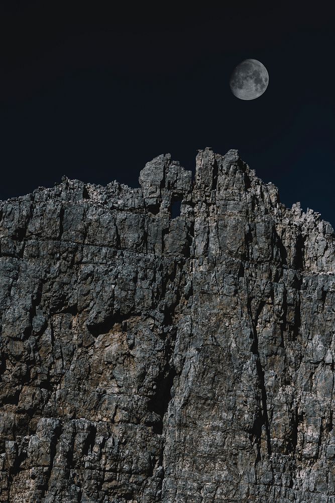 The moon over a rugged mountain cliff