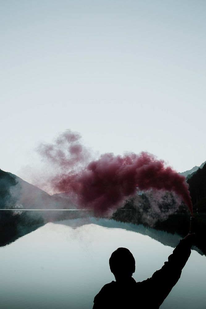 Man with a pink smoke stick by the lake of Antholz, Italy