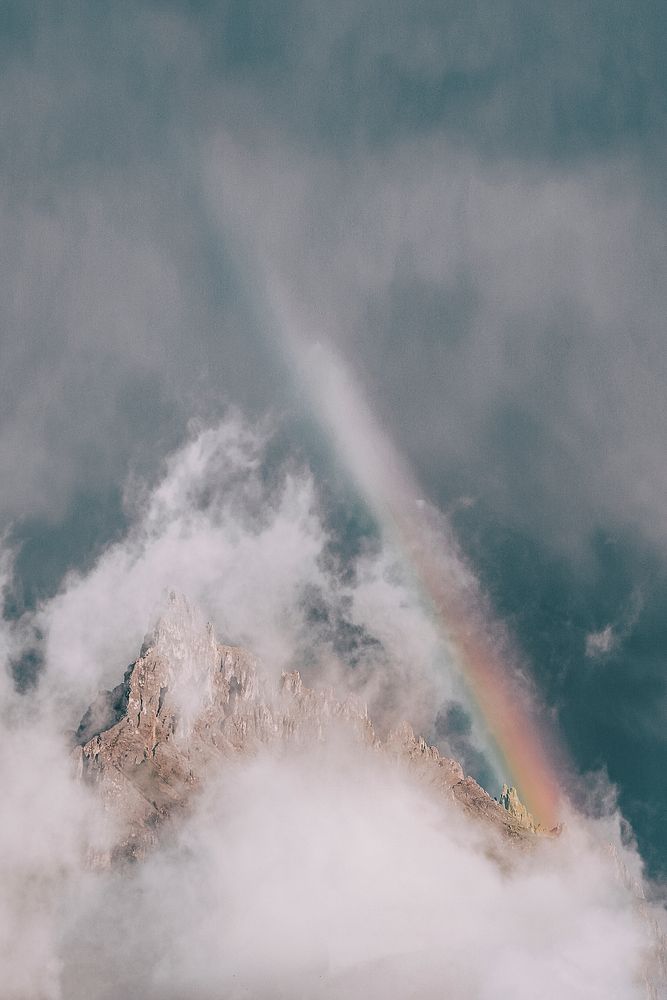 Mist and a rainbow over a rugged mountain in Alpe di Siusi, Dolomites, Italy
