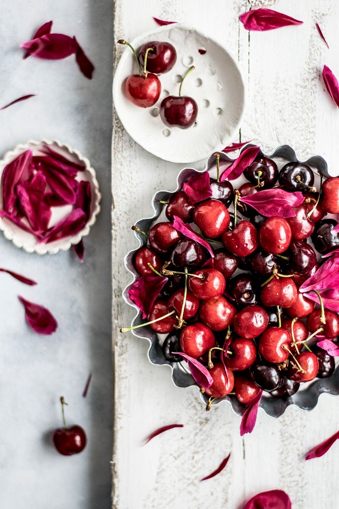 Tray filled with fresh cherries and flower petals. Visit Monika Grabkowska to see more of her food photography.