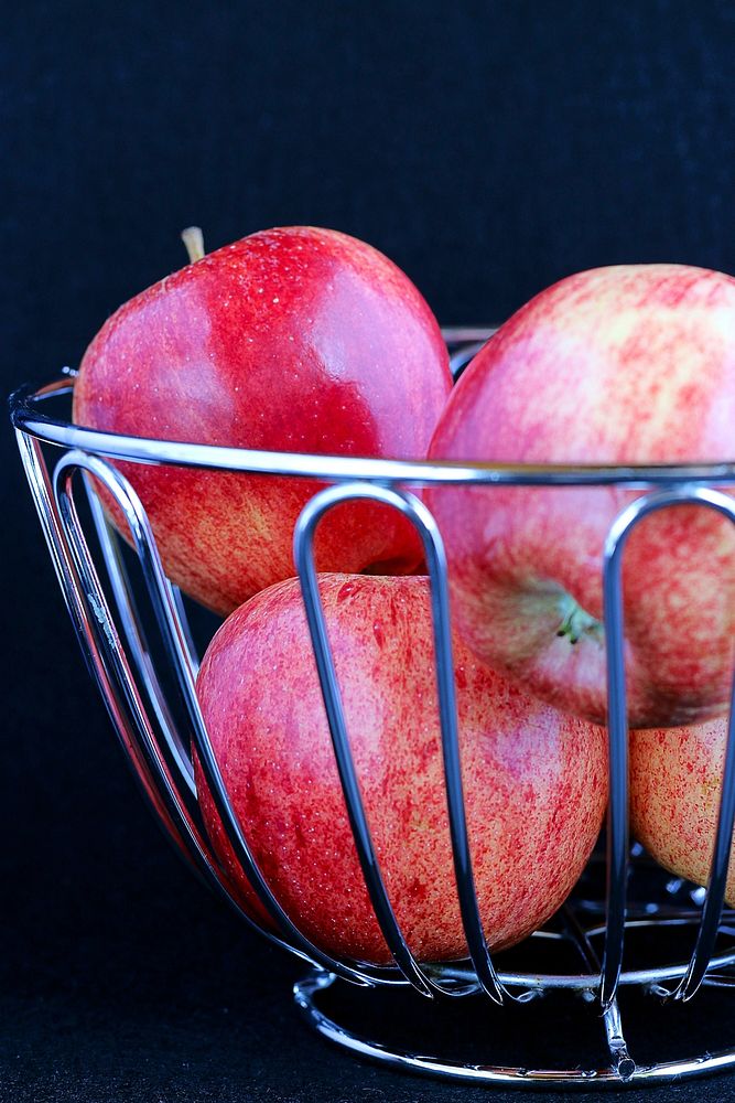 Medium close up of steel basket holding apples.