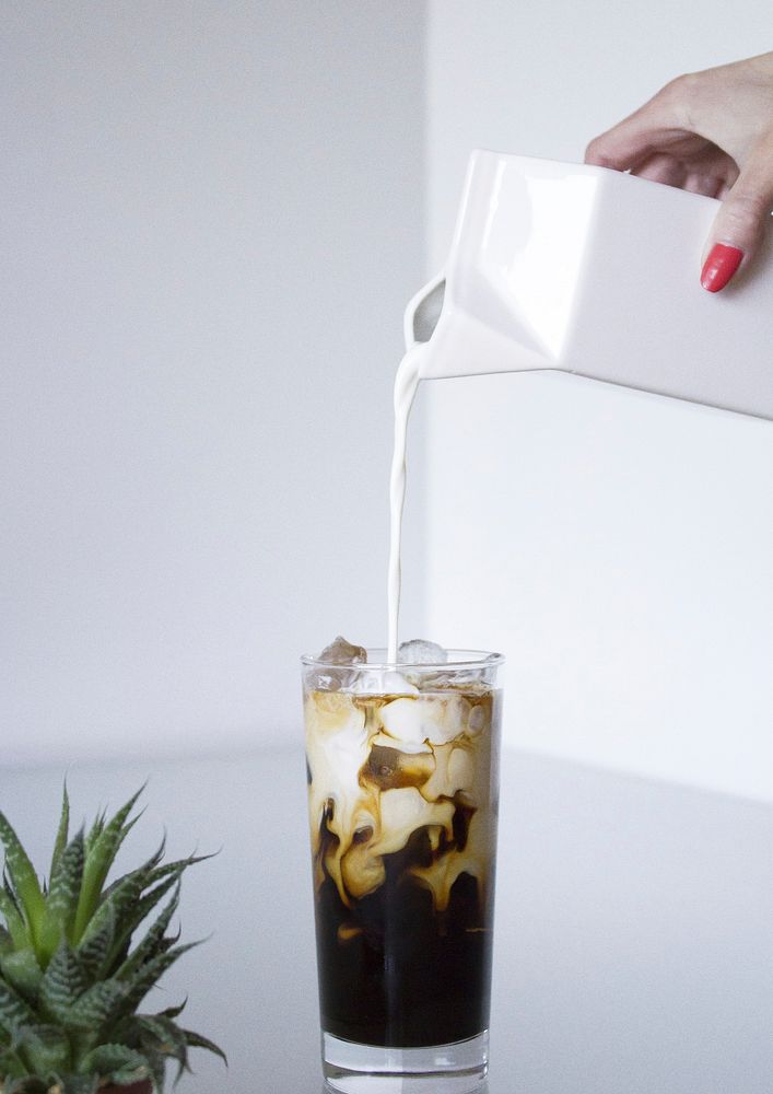 Free pouring milk into ice coffee glass on white background photo, public domain beverage CC0 image.