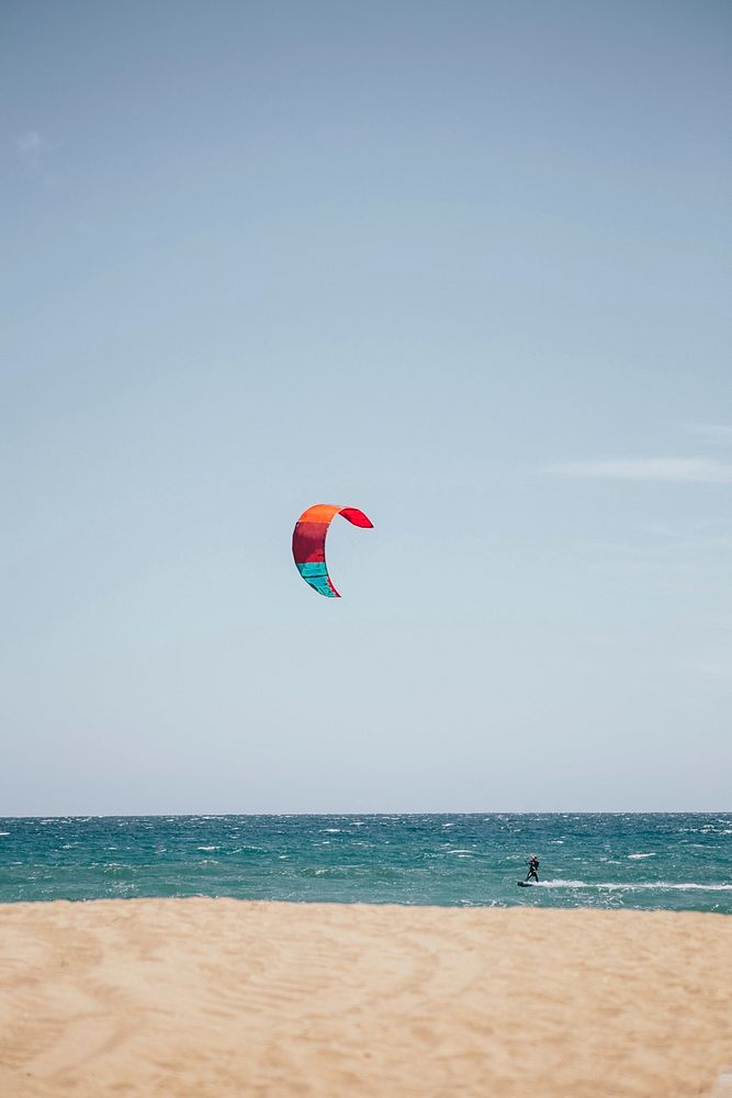 Kitesurfing on a windy day. The ocean is host to some choppy waves behind the sandy beach making for a fun ride for the…