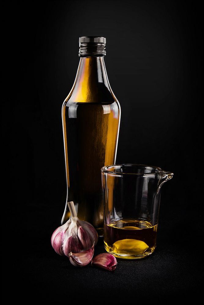 Free olive oil bottle with garlic in black background public domain CC0 photo.