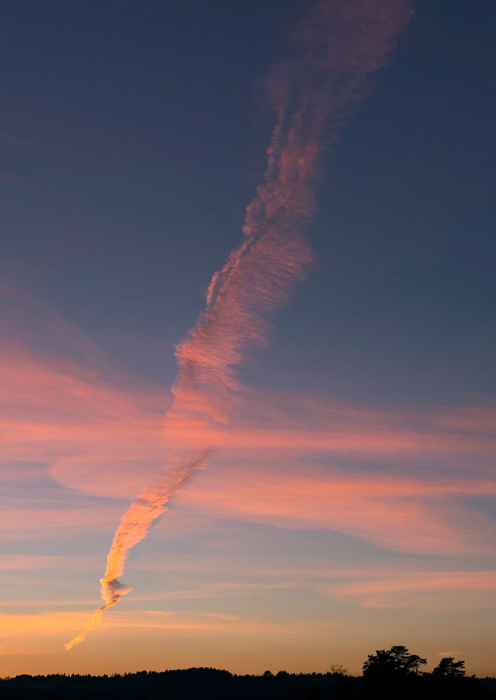 Elongated smoke plume from the oil refinary crossing clouds at sunset 1