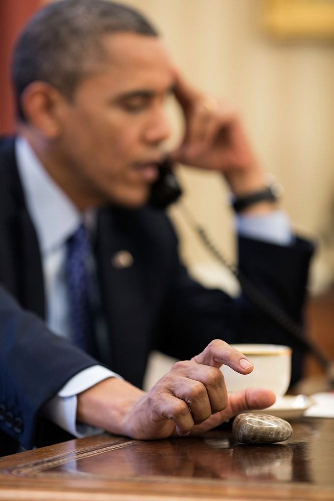 President Barack Obama plays with a Petoskey stone as he talks on the phone in the Oval Office, Dec. 6, 2012.