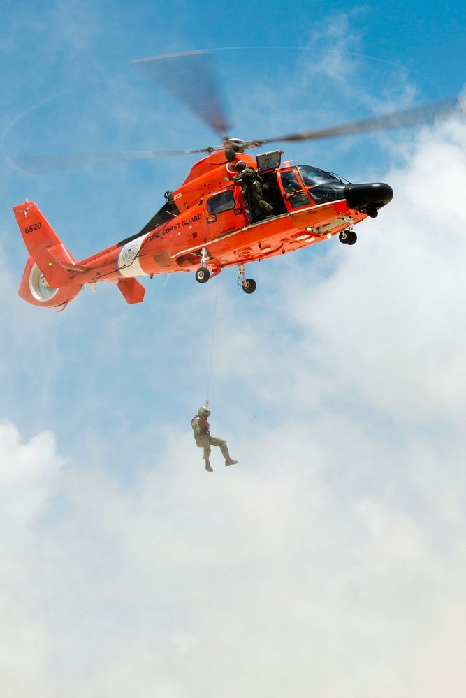 A U.S. Coast Guard rescue swimmer is lowered to a beach from an MH-65 Dolphin helicopter at San Luis Pass in Texas, May 24…