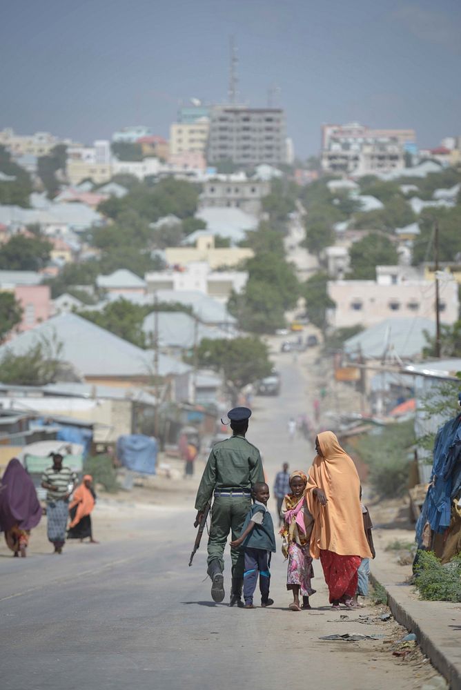 A member of the Somali Police Force walks down a road in Mogadishu with his son on December 21. AU UN IST PHOTO / Tobin…