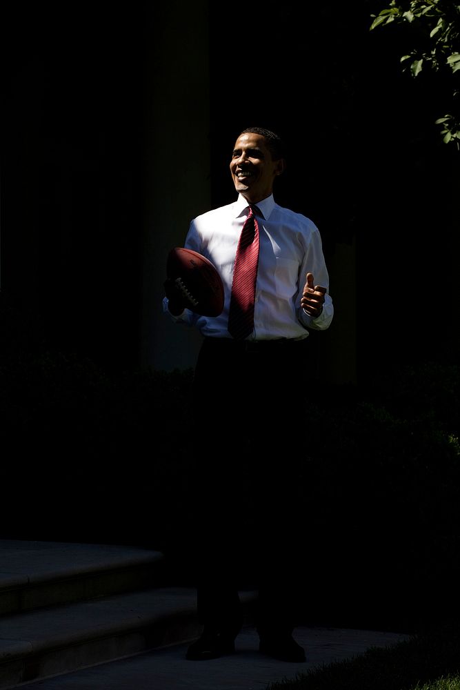 President Barack Obama stands in a shaft of light while playing football outside the Oval Office May 20, 2009.