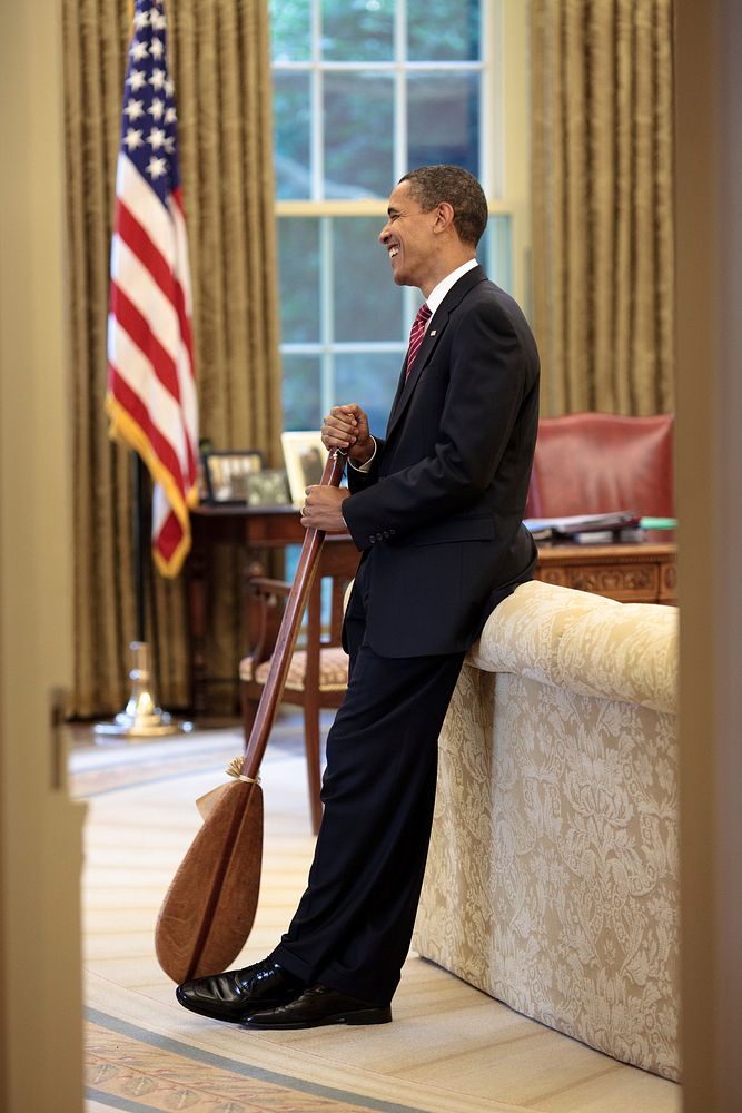 President Barack Obama stands in the Oval Office with a Hawaiian paddle that was given to him as a gift by chef Allen Wong…
