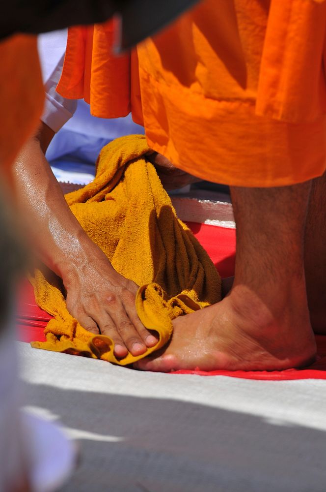 Person washing monk's feet. Free public domain CC0 image.